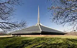 Exterior view of the church's roof and spire from a grassy berm