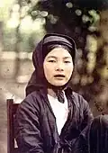 A northern Vietnamese girl with black teeth sitting on a chair.