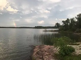 Photo from shore of a lake. Some rocks and greenery are in the right-side foreground.