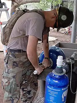 A utilitiesman attaching a water purifier to a water pump in Cantón El Sunza