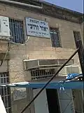 Exterior sign stating that the synagogue was supported by philanthropist Yamin Ben Harroch, and founded in the year 1927.