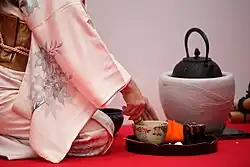 A hostess prepares matcha during a Japanese outdoor tea ceremony.