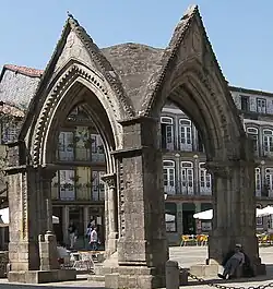 A covered stone building with four columns and arches