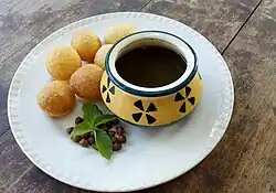 A bowl of a dark red, watery sauce next to some small, round balls of crispy dough