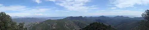 Succession of low mountain ranges down to the sea, visible on the horizon, blue sky