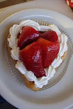 A heart-shaped pastry topped with white icing and sliced strawberries.