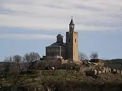 View of a medieval church and bell tower topping a hill surrounded by medieval ruins