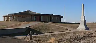 Low circular building atop hill; small obelisk nearby