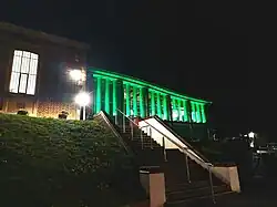 Performing Arts Centre illuminated green at night, from School Lane. The Maggs Library is to the left.
