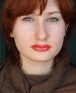 A person whose lips appear to have pink lipstick applied, but it is permanent makeup.