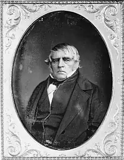 A stern-looking man in a suit in the style of the mid-18th century