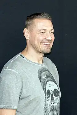 profile photo of a grinning Petr Jákl, wearing a grey print t-shirt
