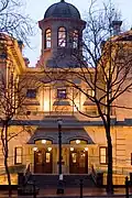 Photograph of the Pioneer Courthouse at dusk, illuminated in golden light with the cupola silouetted against the darkening sky.