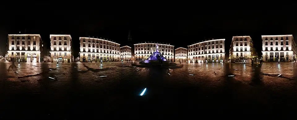 The square at night, deserted, with buildings and the fountain illuminated