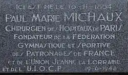 Commemorative plaque on the house where Paul Michaux was born with inscription: "Here was born the 16-11-1854 Paul Marie Michaux, Surgeon of Paris Hospitals Founder of Gymnastics and Sports Federation of France and Sponsorships Union Jeanne Lorraine and UIOCP 19-6-1948."[c]