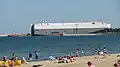 Car carrier in the entrance to the inner port, as seen from the nearby beach
