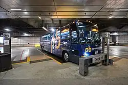 A blue motorcoach parked at an angled bus berth inside a structure