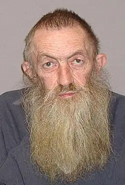Popcorn Sutton against a grey background, displaying his long, wispy beard