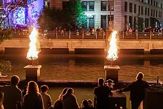 People line the river to quietly sit and watch the burning braziers