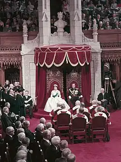Queen Elizabeth II (in ball gown) and Prince Philip (full dress uniform) before the formal (full dress) opening of the Parliament of Canada (1957), surrounded by participators of varying degrees of formal attire (morning dress, white tie etc.), presumably in accordance with their functions or time of arrival and departure