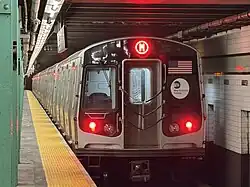 An R179 M train stops at Forest Hills–71st Avenue station