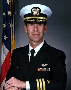 A color portrait photo of a smiling white man, looking into the camera, wearing a Navy admiral's uniform