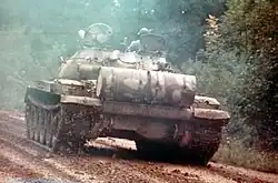 Rear view of a T-62A tank under way with cylindrical unditching beam stowed at rear