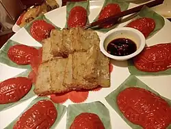 Large banquet plate with unadorned radish cake slices, small oval ang ku kueh (red tortoise cakes), a small bowl of dipping sauce and a pair of chopsticks