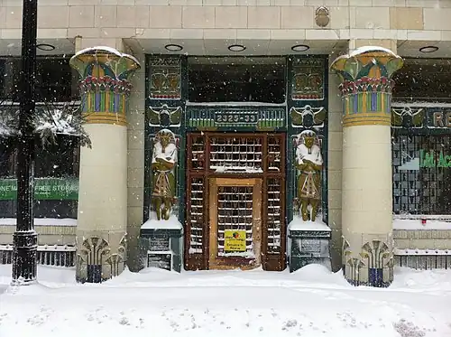 Snow-covered entrance with colorful Egyptian Revival columns and pharaoh statues flanking doorway