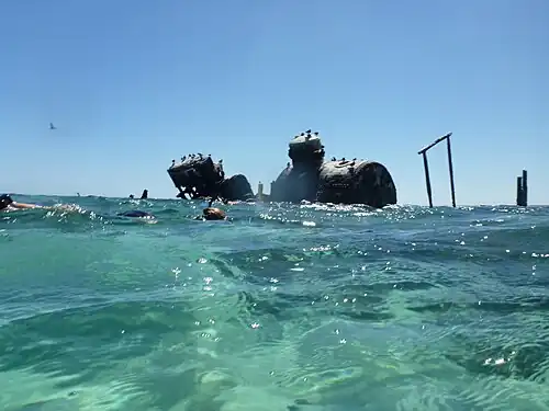 Snorkelers explore a ship wreck adjacent to the coral reef