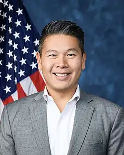 Official House portrait of Tran smiling in front of the U.S. flag, wearing a gray suit and light blue shirt.