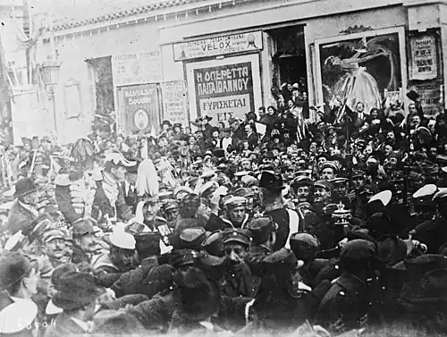 A large crowd of people, including a few armed guards