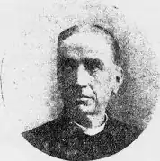 Black-and-white photograph of a man wearing a clerical collar, facing slightly to the left.