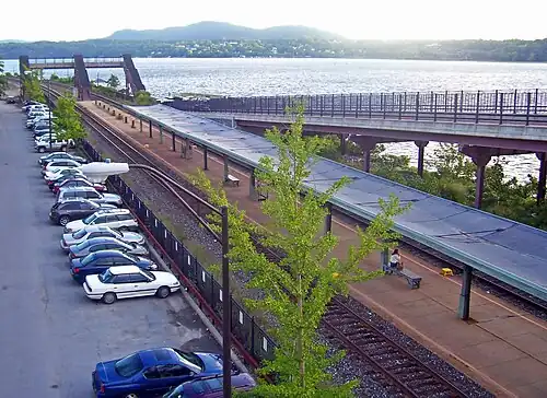 A covered railway station platform with two tracks next to a wide river