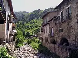Photo of a dry, rocky streambed running straight through a town of old buildings