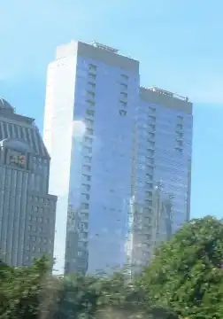 Photograph of the outside of the Ritz-Carlton Jakarta hotel at night including the road in front of it and a few other buildings