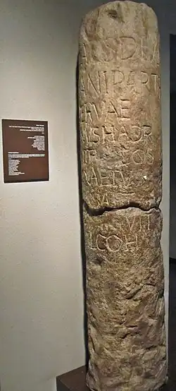 Tall stone milestone with a worn Latin inscription, displayed upright in a museum setting