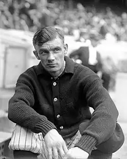 A man in a dark sweater and light baseball pants