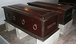 Two dark wooden coffins with metal ring handles, belonging to Johann Wolfgang von Goethe and Friedrich Schiller, displayed on stone supports in the Ducal Vault, Weimar.