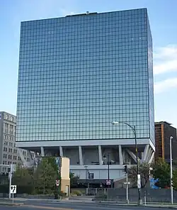 A glass office building slightly cantilevered over its base, giving it the appearance of being on stilts