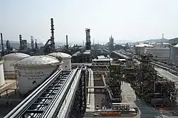 Many large metal structures, cylindrical tanks and chimneys next to a large road