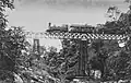 A photo shows a 2-6-0T SS300 class steam engine (later type C11) hauled an SS inspection car passing a bridge on the Bangil-Malang railway line