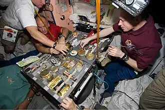 STS-129 crew members using specialised tableware for a meal in the International Space Station (2009)