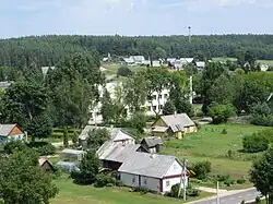 Image of a rural village with four houses in the foreground set against some short green trees.
