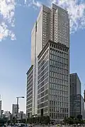 Ground-level view of a boxy, gray high-rise