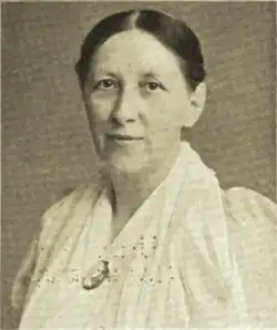 19th-century B&W portrait photo of a woman with her hair in an updo, wearing a white blouse.