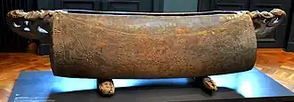 A garamut with geometric carvings in the central portion and handles carved with human figures