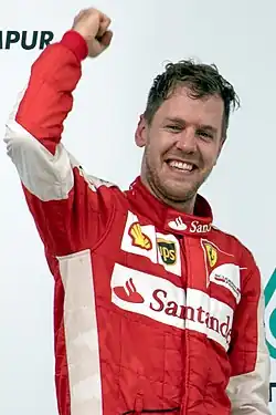 A picture of Sebastian Vettel cheering on the podium after winning the 2015 Malaysian Grand Prix for Ferrari.