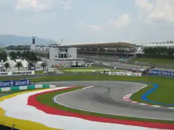 Asphalt Formula 1 track at a chicane, with grandstands in the background