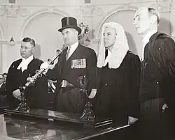 Man in top hat holds the mace standing by 3 other men